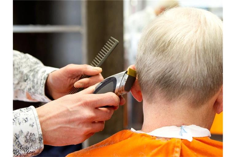 Ein Friseur schneidet einem Kunden die Haare. Foto: picture alliance/dpa/Archivbild