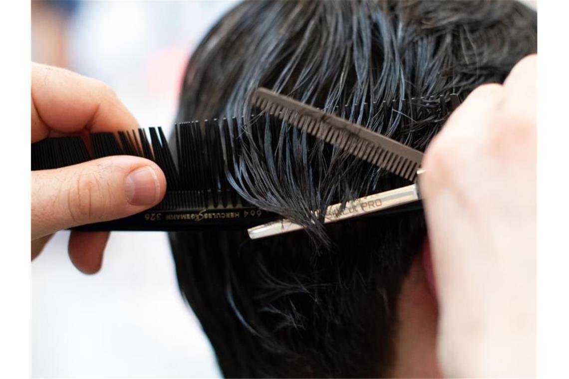 Ein Friseur schneidet einer Kundin mit einer Schere die Haare in einem Friseur-Salon. Foto: Symbolbild Friseur/dpa/Symbolbild