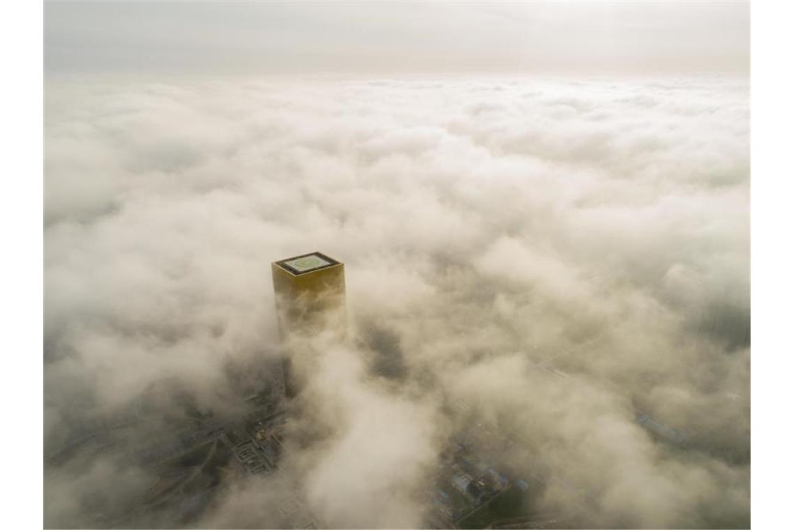 Peking sieht Versagen der Energieaufsicht im Klimaschutz Ein Gebäude mit einem Hubschrauberlandeplatz ragt aus dem Smog über Pekings Innenstadt hervor. Foto: Xu Jingbo/SIPA Asia via ZUMA Wire/dpa