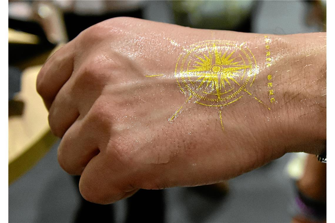 Ein goldenes, temporäres Kompass-Tattoo konnten sich die Konzertbesuchenden auf ...