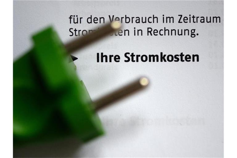 Ein grüner Stromstecker liegt auf einer Stromrechnung. Foto: Jens Kalaene/dpa-Zentralbild/dpa/Archiv/Illustration