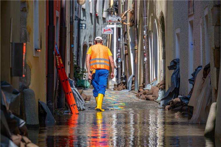 Ein Helfer geht, nachdem das Hochwasser der Donau im bayerischen Passau etwas zurückgegangen ist, durch eine Gasse mit Sandsäcken vor den Häusern.