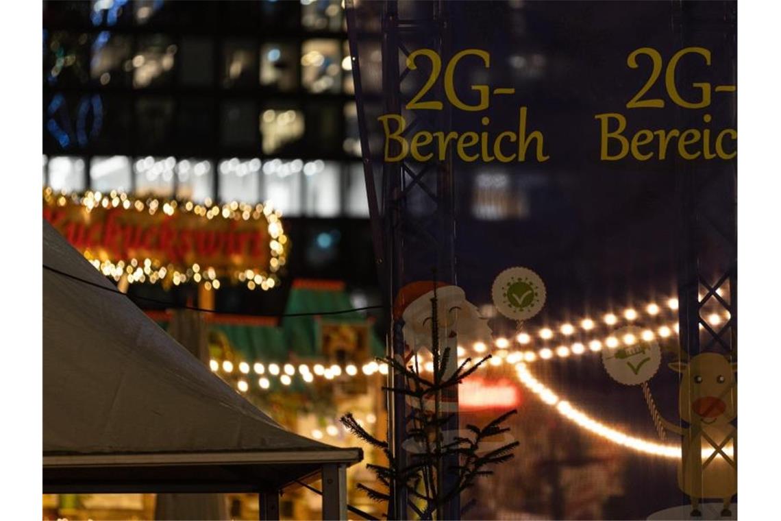 Bummeln mit Abstand und Maske - Weihnachtsmärkte öffnen Ein Hinweis auf einen 2G-Bereich hängt auf dem Frankfurter Weihnachtsmarkt zwischen Lichterketten. Foto: Hannes P. Albert/dpa