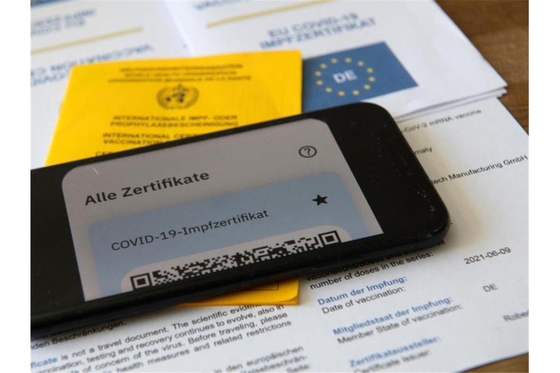 Ein Impfpass und ein Smartphone, auf dem die App CovPass läuft. Foto: Stefan Puchner/dpa/Illustration