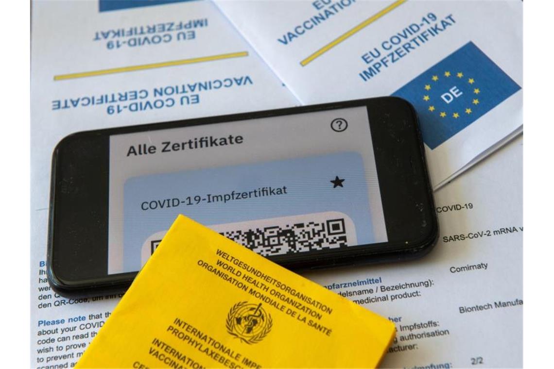 Ein Impfpass und ein Smartphone mit der CovPass-App liegen auf einem Impfzertifikat. Foto: Stefan Puchner/dpa/Symbolbild