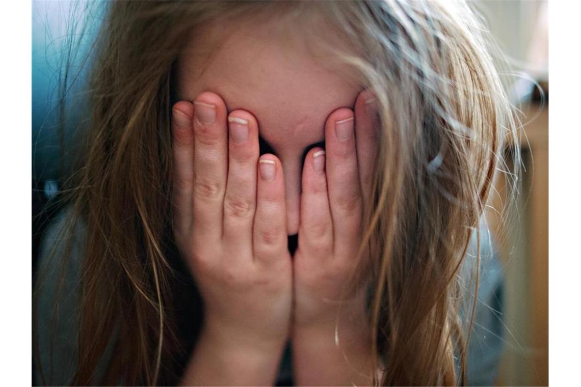 Zustimmung zu körperlicher Gewalt gegen Kinder weiter hoch Ein junges Mädchen hält sich die Hände vor ihr Gesicht. Foto: picture alliance / Nicolas Armer/dpa/Archivbild