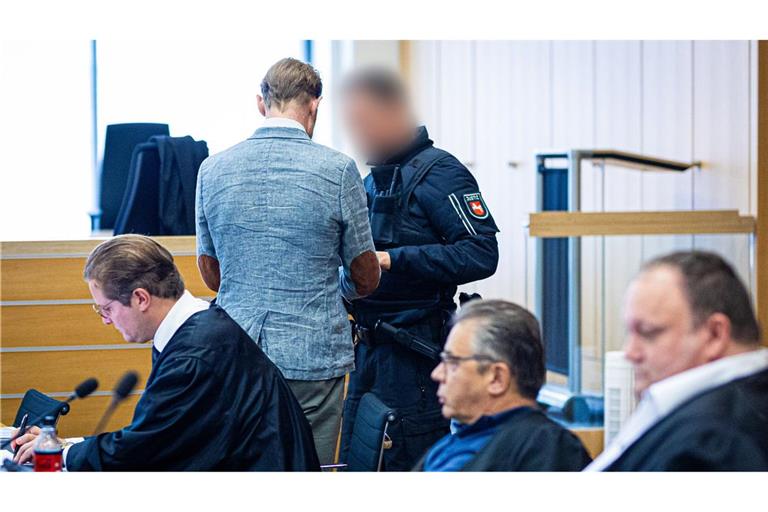 Ein Justizmitarbeiter (oben rechts) löst bei dem Angeklagten Christian B. (oben links) in einen Gerichtssaal im Landgericht die Handfesseln. (Archivbild)