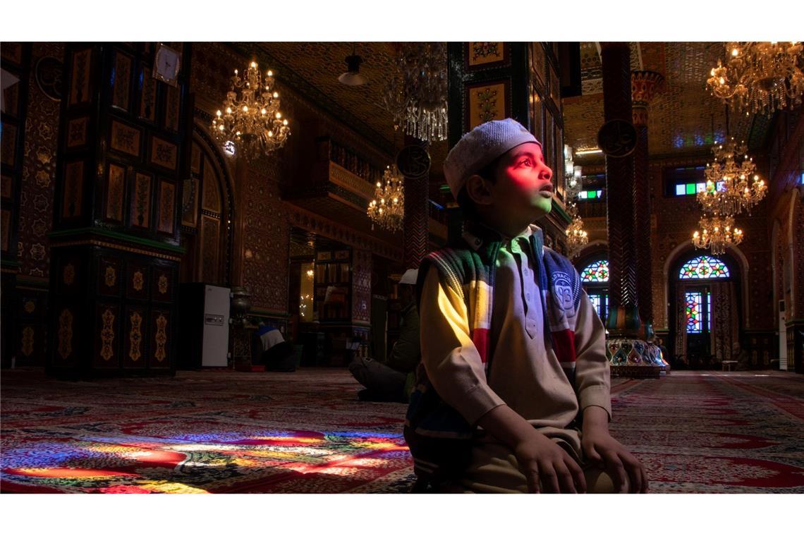 Ein kaschmirischer muslimischer Junge sitzt am dritten Tag des islamischen Fastenmonats Ramadan vor einem Schrein und posiert für ein Foto.