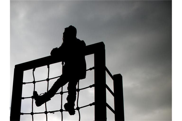 Ein kleines Mädchen spielt an einem Klettergerüst vor dunklem Himmel. Foto: Julian Stratenschulte/dpa/Symbolbild