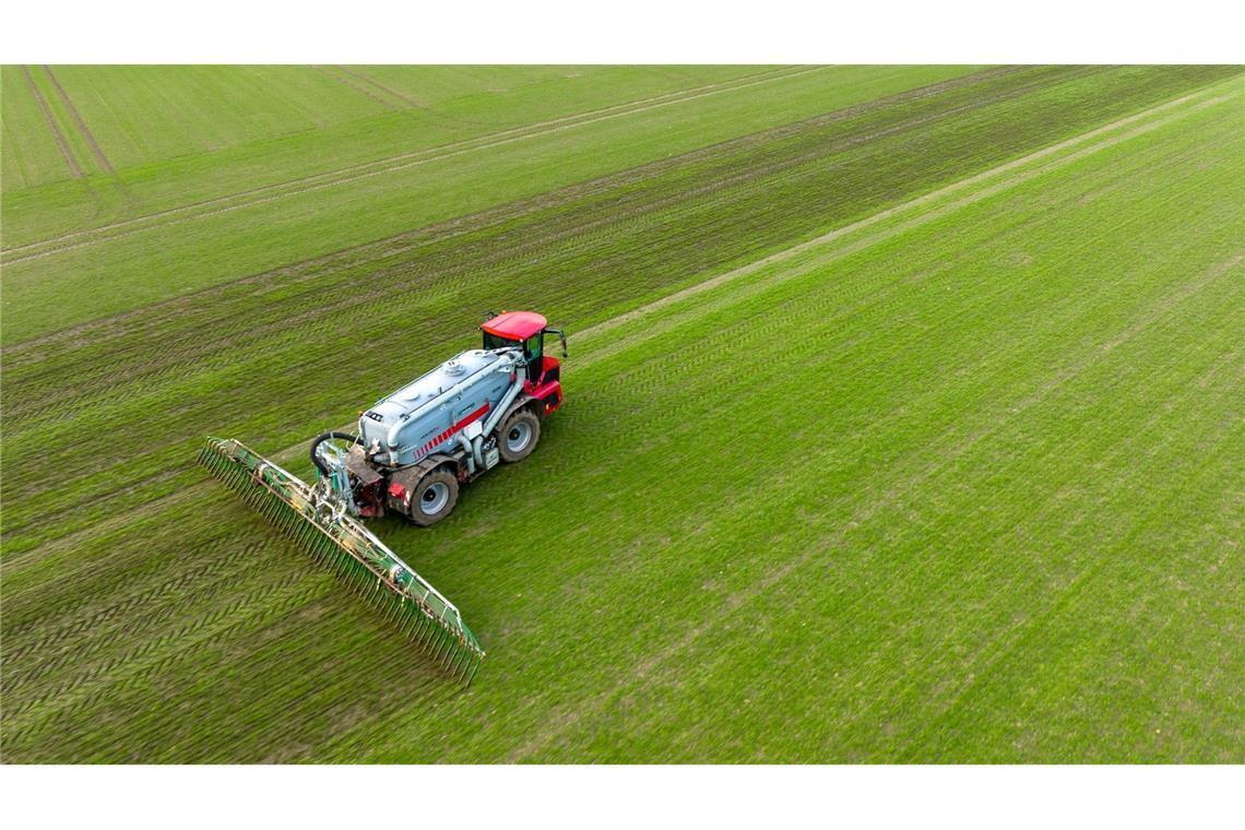 Ein Landwirt bringt mit seinem Gespann Gülle im sogenannten Schleppschuh Verfahren auf einem Feld aus.