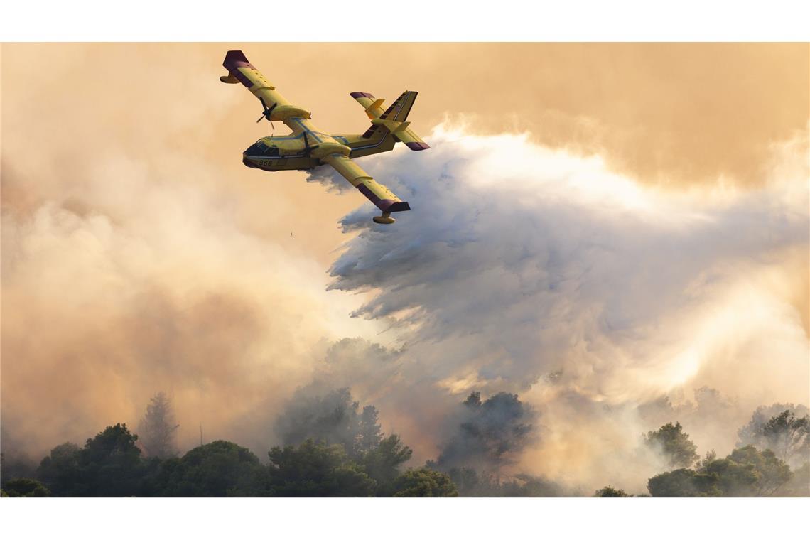 Ein Löschflugzeug versprüht Wasser, um einen Waldbrand auf der Insel Ciovo zu löschen (Archivfoto).