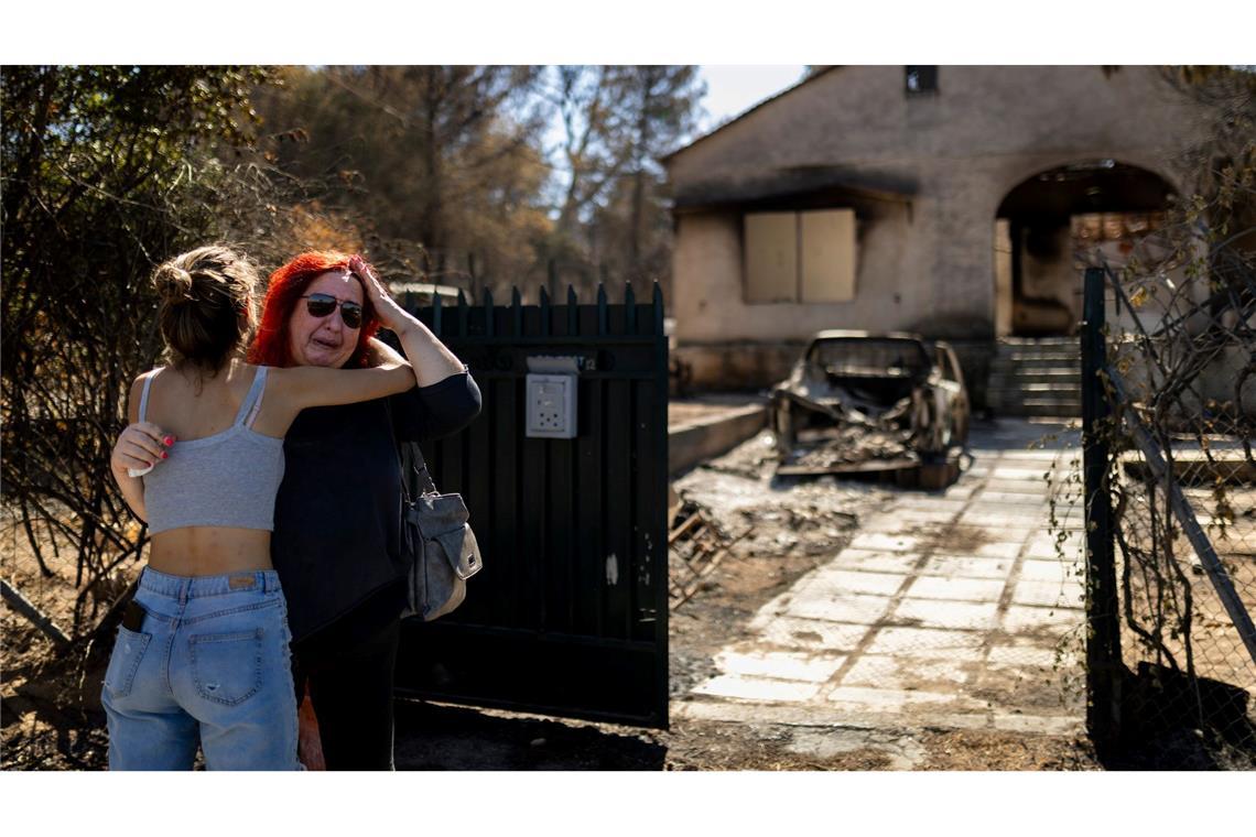 Ein Mädchen tröstet eine Frau, nachdem deren Haus im Norden von Athen durch einen Waldbrand schwer beschädigt wurde. Verheerende Brände halten Griechenland in Atem. Viele Häuser brannten ab.