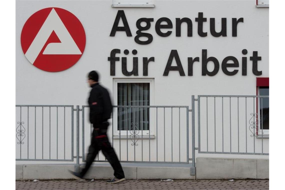 Ein Mann geht an dem Logo der Agentur für Arbeit vorbei. Foto: Sebastian Kahnert/dpa-Zentralbild/dpa/archivbild