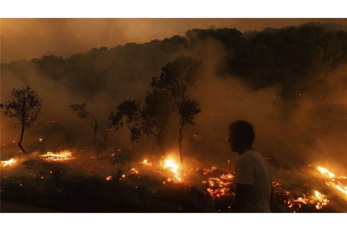 Ein Mann geht im August 2023 nahe der Flammen eines brennenden Waldes im Dorf Dikela in der Nähe der Stadt Alexandroupolis.