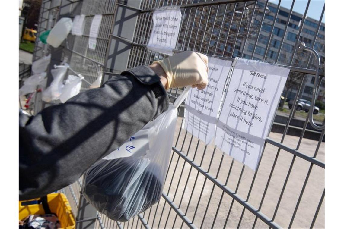 Ein Mann hängt eine Tüte an einen Zaun am Marienplatz. Foto: Marijan Murat/dpa