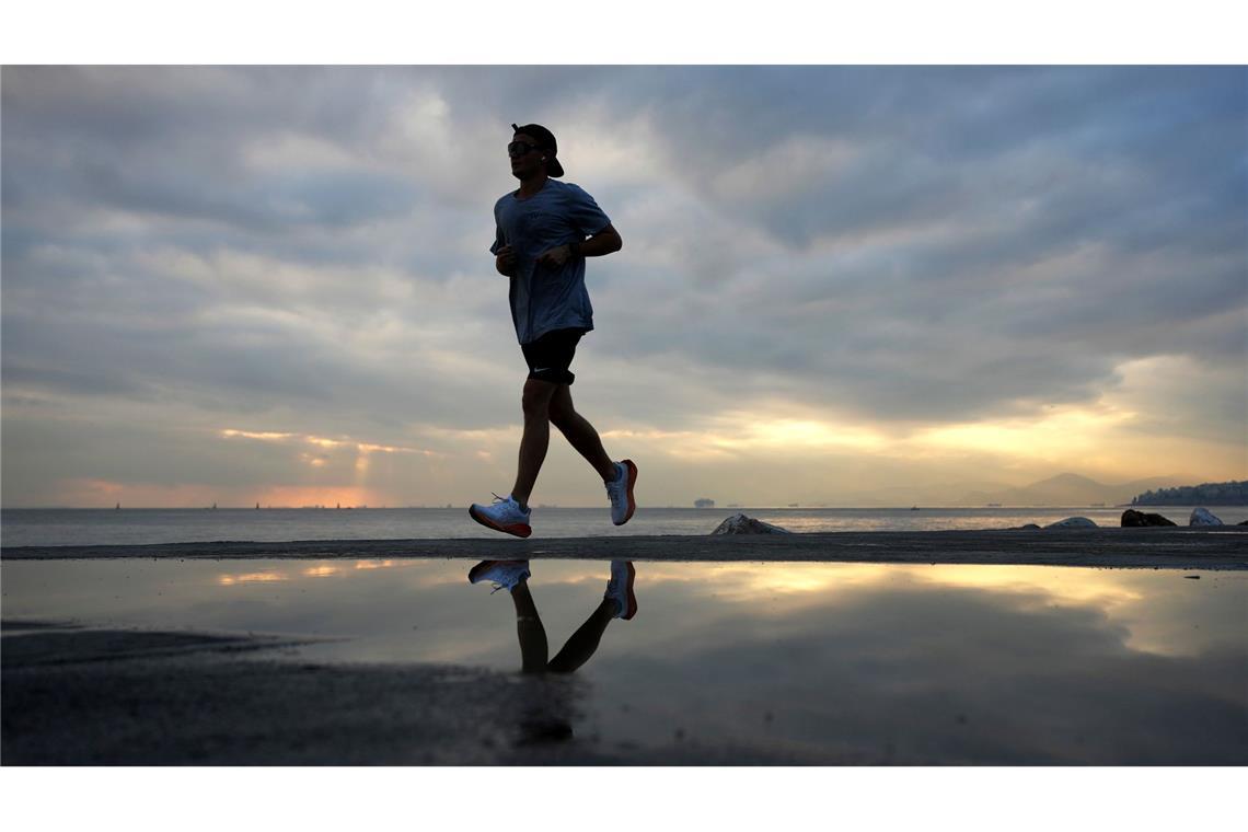 Ein Mann joggt bei Sonnenuntergang nach einem regnerischen Tag in Paleo Faliro, einem Vorort am Meer im Süden Athens.