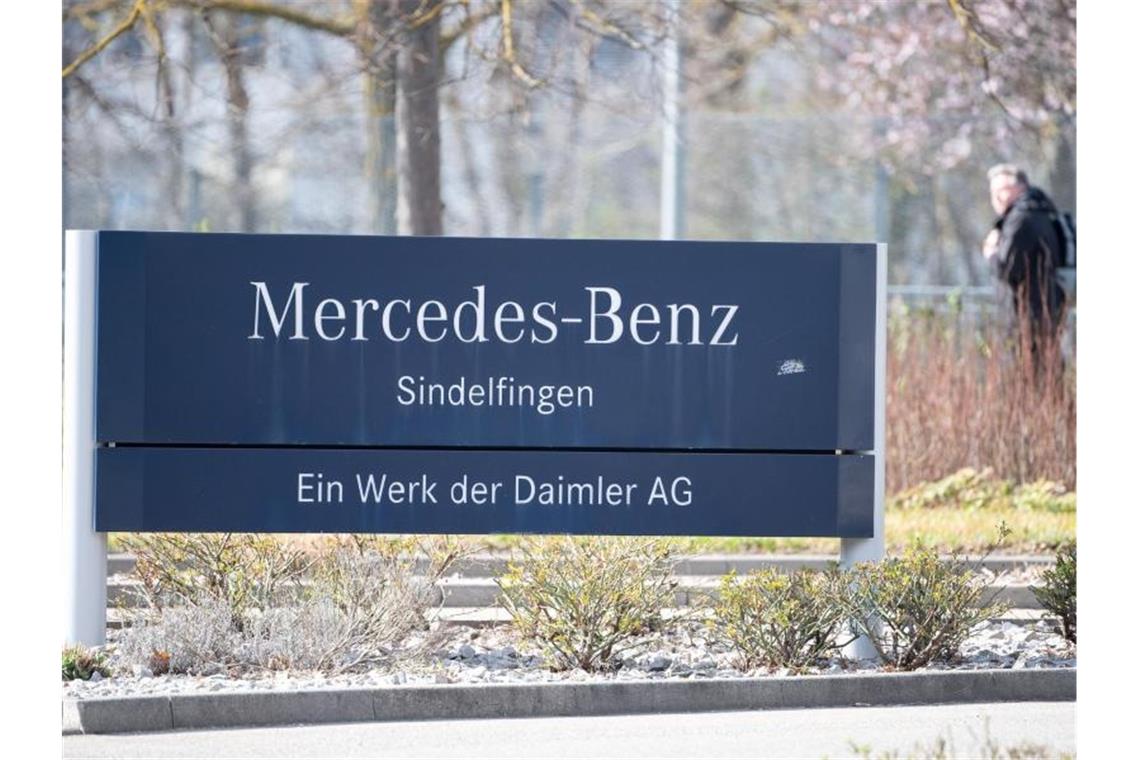 Ein Mann läuft hinter einem Schild mit der Aufschrift „Mercedes-Benz Sindelfingen“ vorbei. Foto: Sebastian Gollnow/dpa/Archivbild