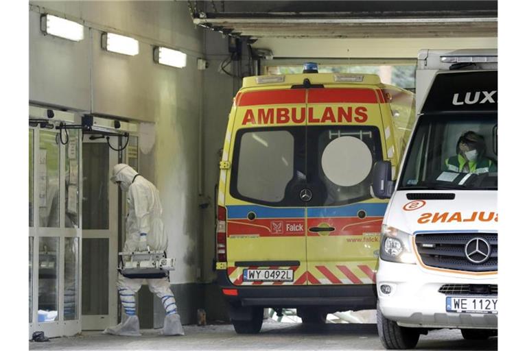 Ein Mann mit Schutzkleidung geht in Warschau in ein auf Corona-Fälle spezialisiertes Krankenhaus. Foto: Czarek Sokolowski/AP/dpa