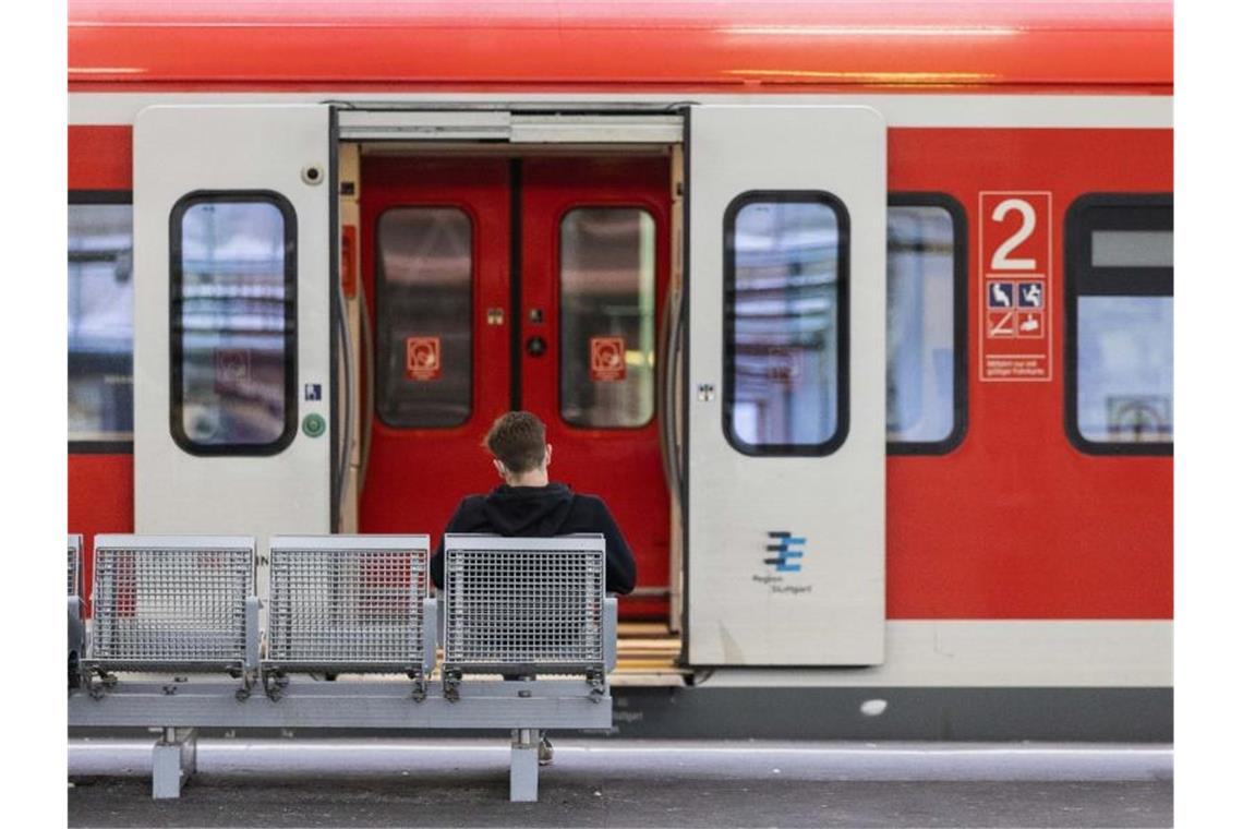 Ein Mann sitzt an einem Bahnhof vor einem Regionalzug auf der Bank. Foto: Tom Weller/dpa/Symbolbild