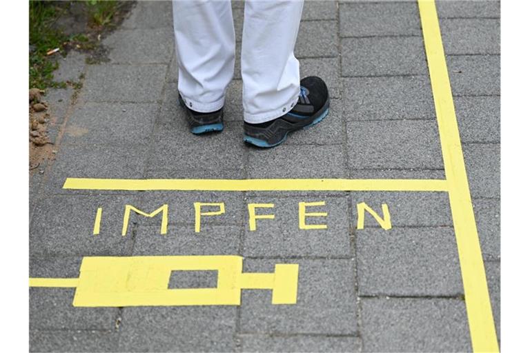 Ein Mann steht an einem Covid-19-Impfcenter hinter der Bodenaufschrift "Impfen". Foto: Arne Dedert/dpa/POOL/dpa/Symbolbild