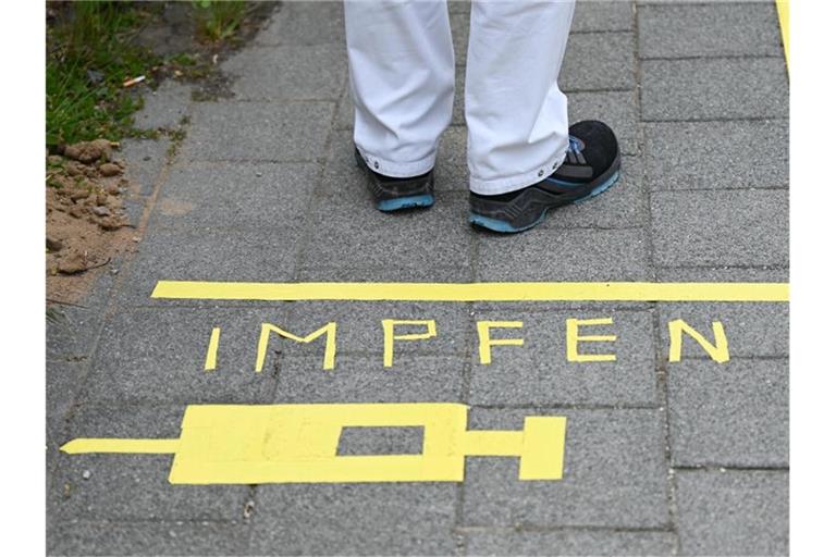 Ein Mann steht an einem Covid-19-Impfcenter hinter der Bodenaufschrift "Impfen". Foto: Arne Dedert/dpa/POOL/dpa/Symbolbild