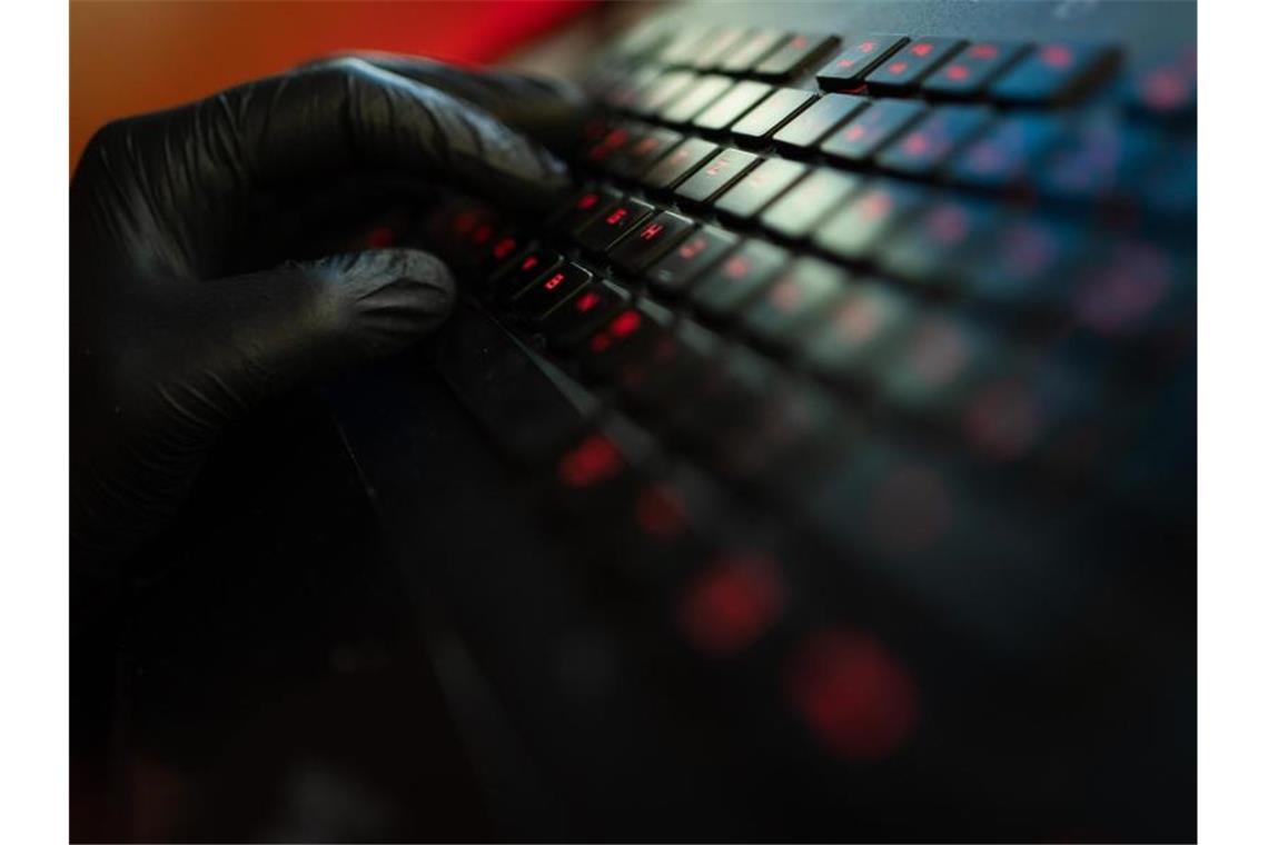Polizei möchte einheitliche Standards gegen Cyberbetrüger Ein Mann trägt Handschuhe und tippt auf der Tastatur eines Computers. Foto: Nicolas Armer/dpa/Archivbild