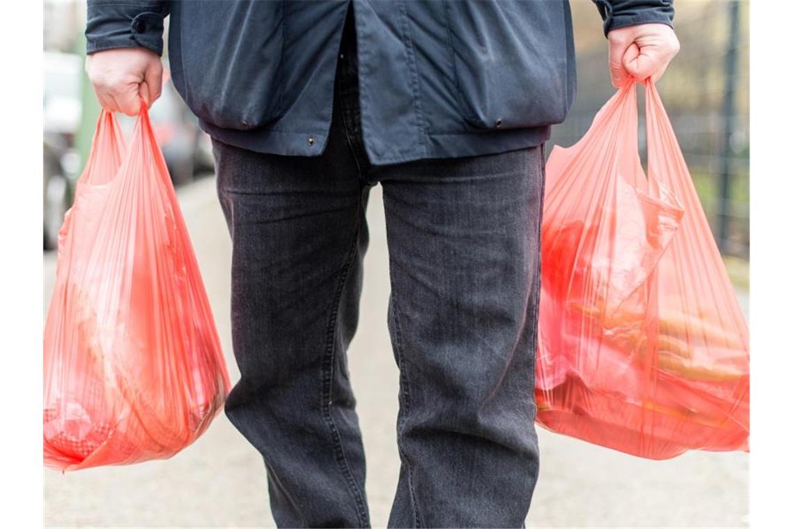 Plastiktütenverbot nimmt letzte Hürde: Verbot ab 2022 Ein Mann trägt seine Einkäufe in Plastiktüten nach Hause. Ab Januar 2022 sind Plastiktüten an Ladenkassen in Deutschland verboten. Foto: Sebastian Gollnow/dpa