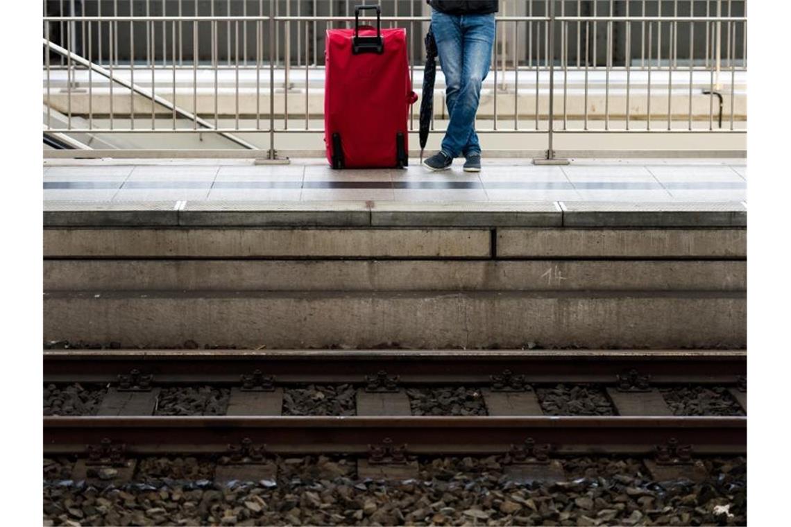 Ein Mann wartet mit seinem Gepäck auf einem Bahnsteig. Foto: Arno Burgi/dpa-Zentralbild/dpa/Symbolbild