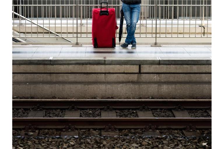 Ein Mann wartet mit seinem Gepäck auf einem Bahnsteig. Foto: Arno Burgi/dpa-Zentralbild/dpa/Symbolbild