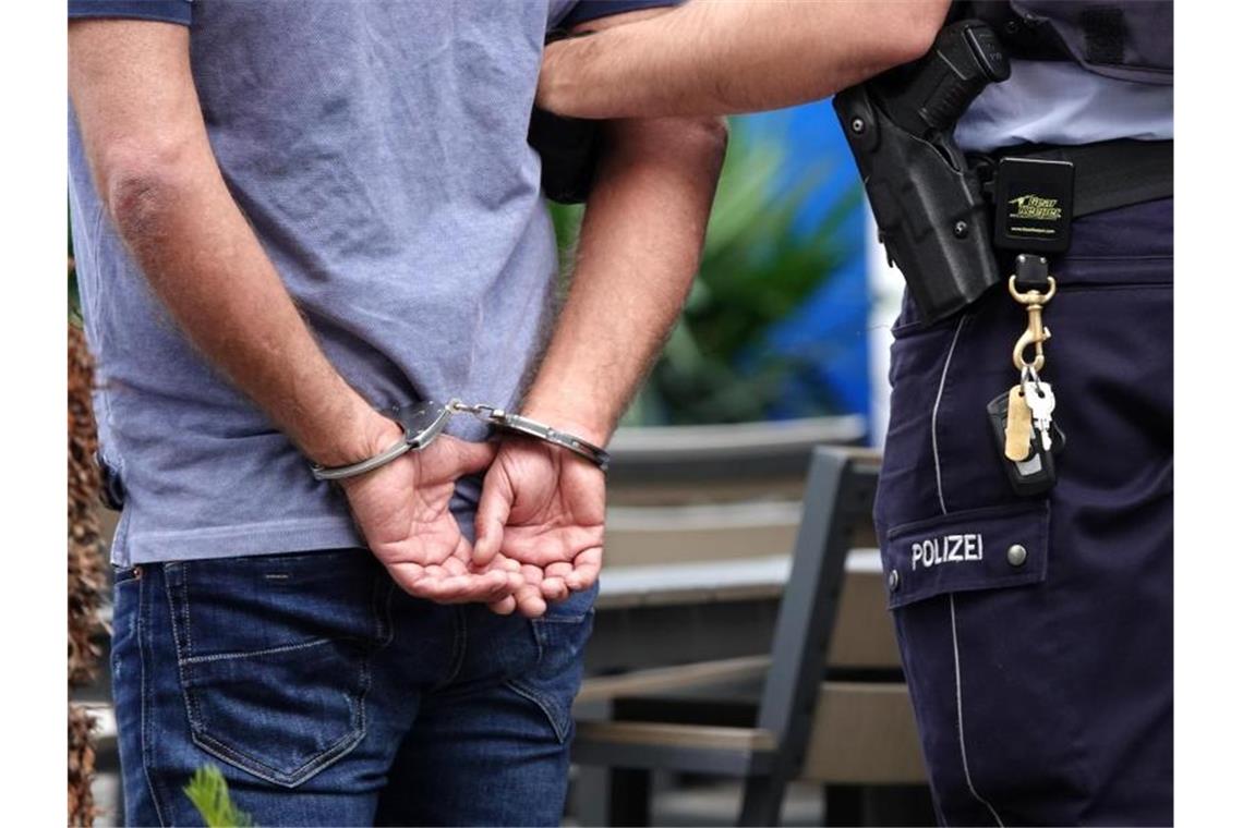 Ein Mann wird in Handschellen abgeführt. Foto: Johannes Neudecker/dpa/Symbolbild