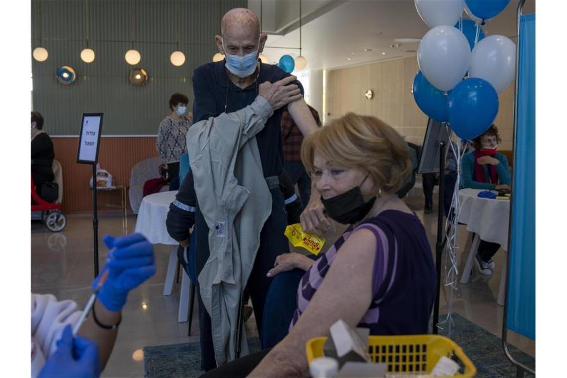 Studie zur vierten Corona-Impfdosis: Gut, aber nicht genug Ein Mann zieht sein Hemd hoch, während seine Frau ihre vierte Dosis des Coronavirus-Impfstoffs in einem privaten Pflegeheim in Petah Tikva erhält. Foto: Ariel Schalit/AP/dpa