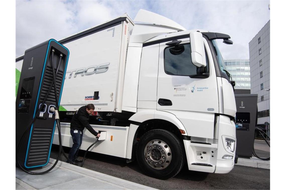 Ein Mitarbeiter der Daimler AG steckt einen Ladestecker in einen eActros. Foto: Marijan Murat/dpa/archivbild