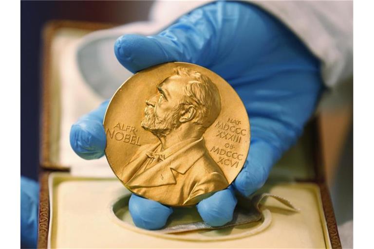 Ein Mitarbeiter der Nationalbibliothek zeigt eine goldene Nobelpreismedaille. Foto: Fernando Vergara/AP/dpa