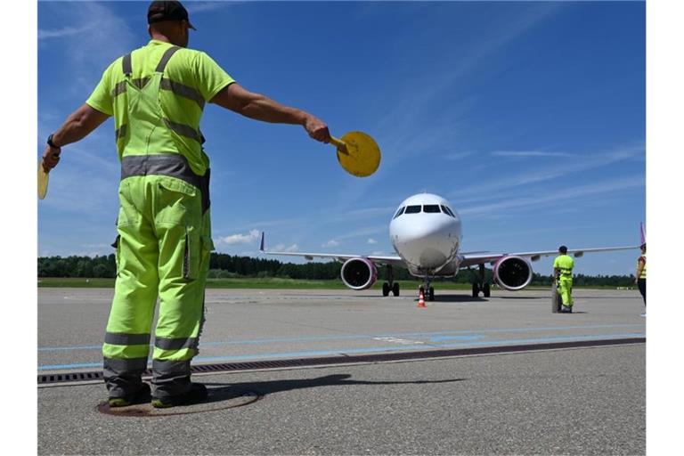 Ein Mitarbeiter des Bodensee-Airports weist das Passagierflugzeug zu seinem Platz. Foto: Felix Kästle/dpa