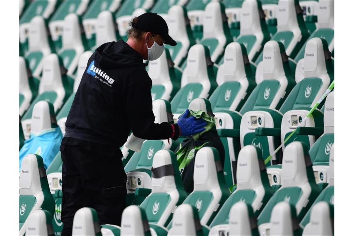 Mediziner: 15 000 bis 20 000 Fans im Stadion „illusorisch“ Ein Mitarbeiter desinfiziert in einem Stadion die Sitzplätze für Ersatzspieler. Foto: Swen Pförtner/dpa/Archiv/Symbolbild