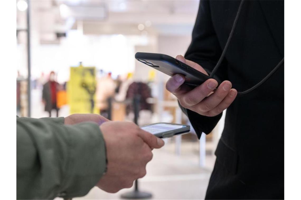 Ein Mitarbeiter eines Kaufhauses kontrolliert am Eingang mit einem Smartphone die Einhaltung der 2G-Regel und den Impfnachweis einer Kundin. Foto: Bernd Weißbrod/dpa/Symbolbild