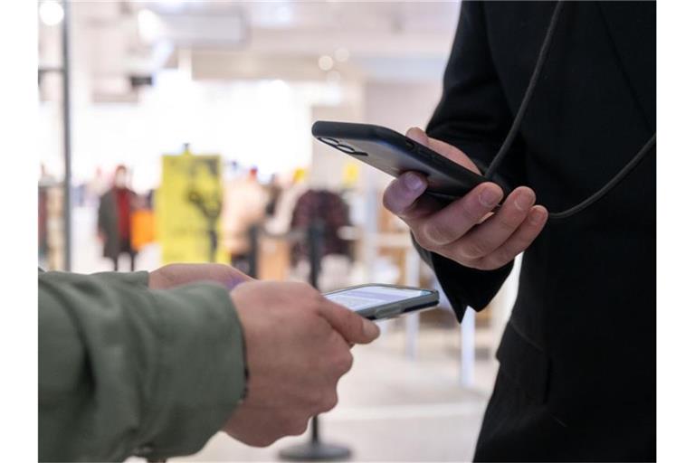 Ein Mitarbeiter eines Kaufhauses kontrolliert am Eingang mit einem Smartphone die Einhaltung der 2G-Regel und den Impfnachweis einer Kundin. Foto: Bernd Weißbrod/dpa/Symbolbild