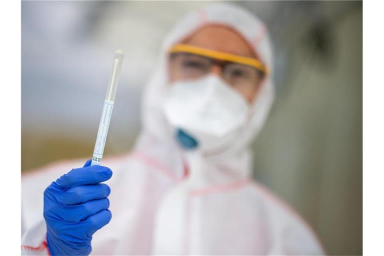 Ein Mitarbeiter hält in einem Abstrichzentrum einen Coronatest-Abstrich in der Hand. Foto: Sebastian Gollnow/dpa/Symbolbild