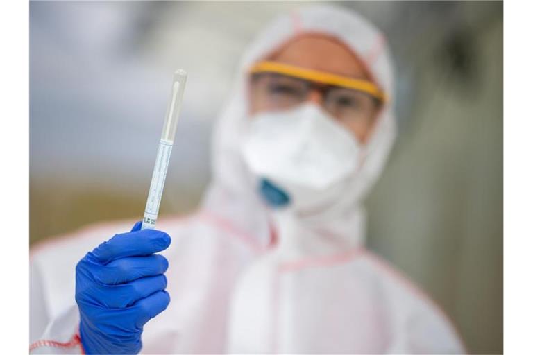 Ein Mitarbeiter hält in einem Abstrichzentrum einen Coronatest-Abstrich in der Hand. Foto: Sebastian Gollnow/dpa/Symbolbild