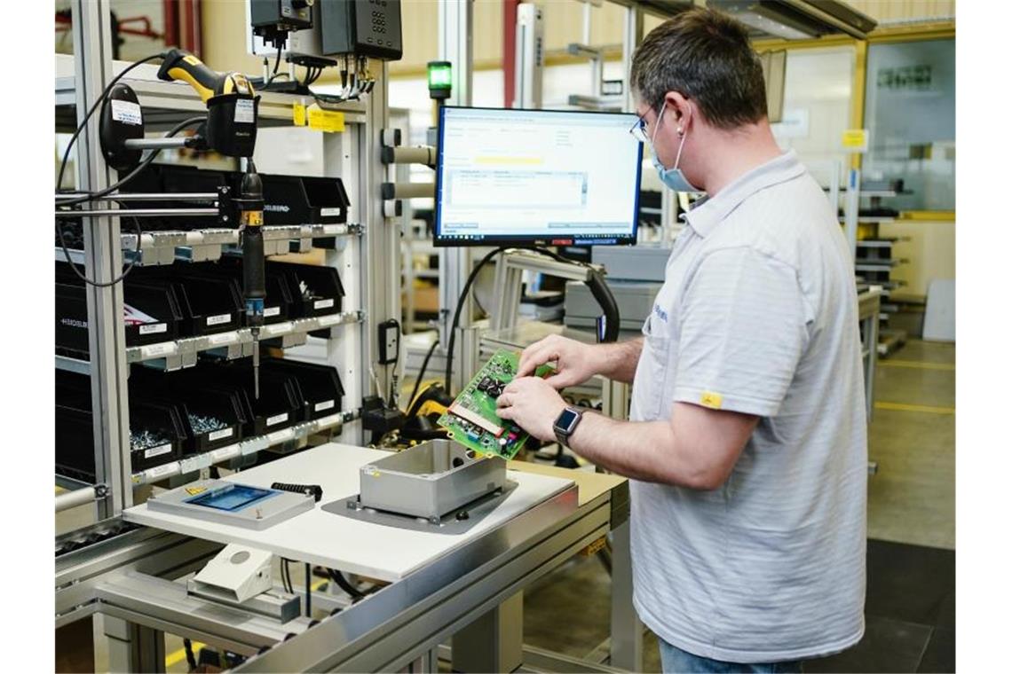 Ein Mitarbeiter montiert im Stammwerk eines Maschinenbauers ein Ladegerät. Foto: Uwe Anspach/dpa/Symbolbild