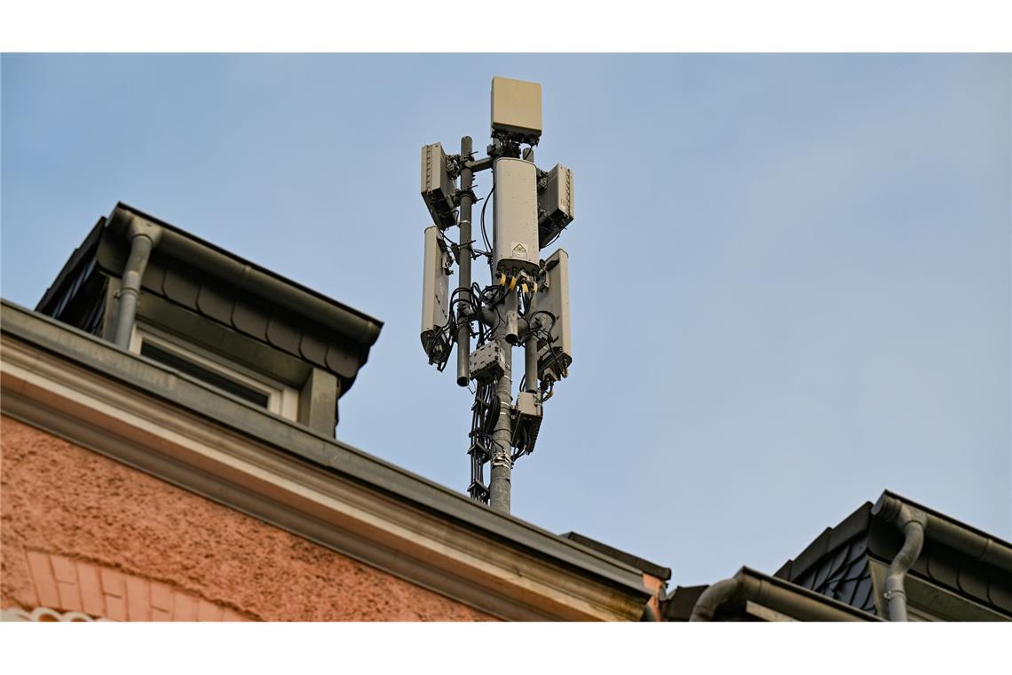 Ein Mobilfunkmast mit 4G/LTE-Antennen (länglich) und 5G-Antennen (quadratisch) steht auf einem Dach eines Wohnhauses.