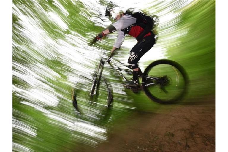 Ein Mountainbiker springt auf dem Canadian Trail bei Freiburg durch den Wald. Foto: picture alliance / dpa / Illustration / Archivbild