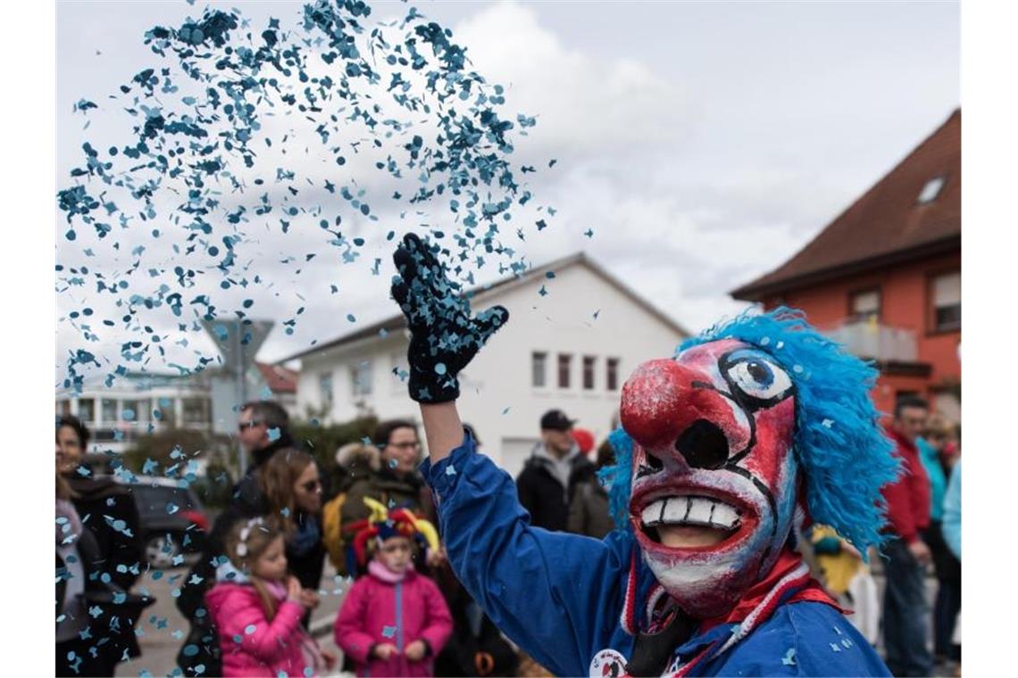 Ein Narr in Waggis-Verkleidung wift bei einem Umzug Konfetti in die Luft. Foto: picture alliance/Patrick Seeger/dpa/Symbolbild