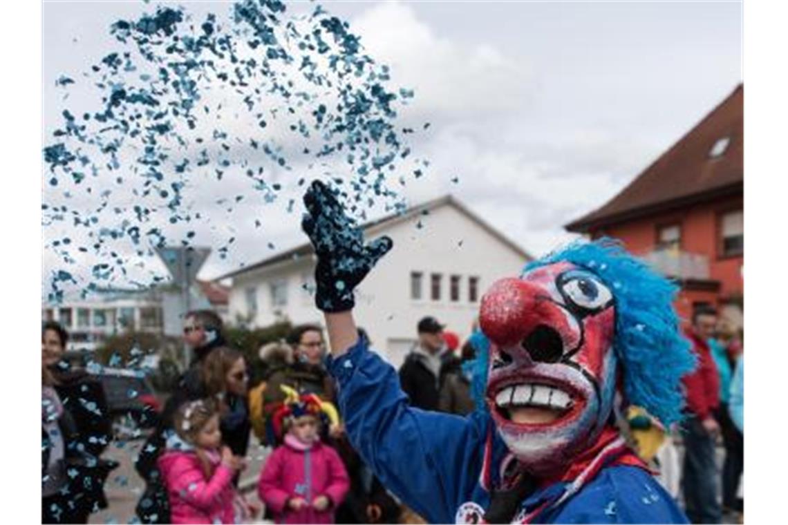 Ein Narr wift beim Umzug der Bauernfastnacht Konfetti. Foto: picture alliance / Patrick Seeger/dpa/Archivbild