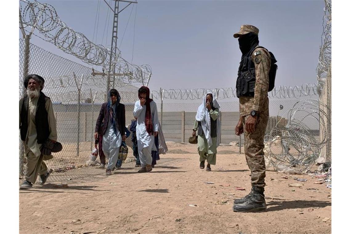 100 Millionen Euro für Flüchtlinge - Hubschrauber nach Kabul Ein pakistanischer Soldat steht Wache, während Menschen aus Afghanistan über einen Grenzübergang in Chaman nach Pakistan einreisen. Foto: Uncredited/AP/dpa