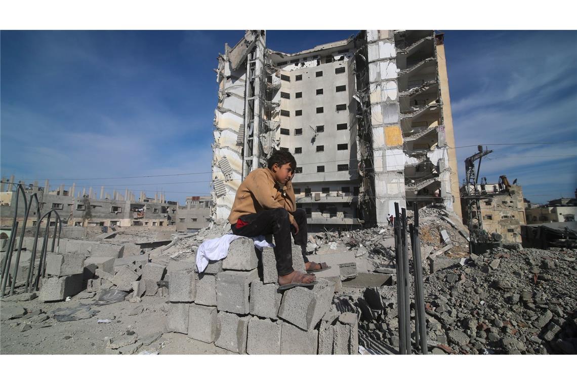 Ein palästinensischer Junge sitzt nach einem israelischen Angriff vor einem zerstörten Wohnhaus im Gazastreifen.
