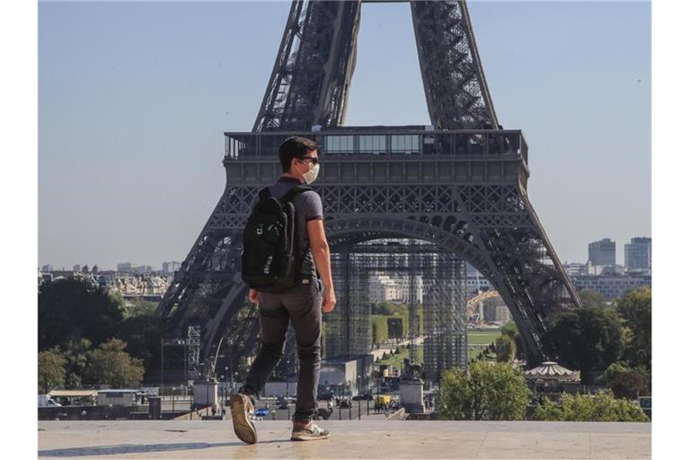 Ein Passant geht mit Mundschutzmaske über den Place du Trocadéro, während im Hintergrund ein Teil des Eiffelturms zu sehen ist. Foto: Michel Euler/AP/dpa