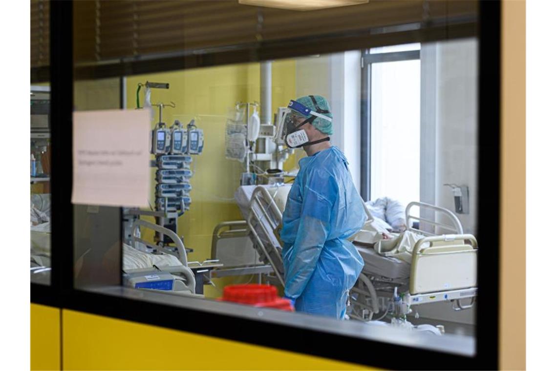 Ein Pfleger versorgt auf einer Covid-19-Intensivstation Corona-Patienten. Foto: Robert Michael/dpa-Zentralbild/dpa/Symbolbild