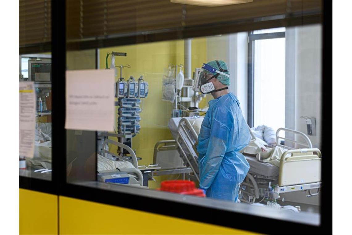 Ein Pfleger versorgt auf einer Covid-19-Intensivstation Corona-Patienten. Foto: Robert Michael/dpa-Zentralbild/dpa/Symbolbild