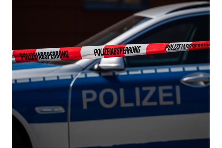 Ein Polizeiauto steht hinter einem Absperrband der Polizei. Foto: Robert Michael/dpa-Zentralbild/dpa